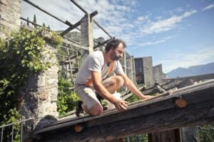 Focused Man Building Roof Of Wooden Construction